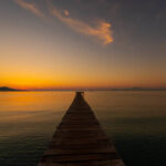 Wooden pier on the beach. Wooden bridge on the beach. Sunrise on the beach, golden hour. Majorca island, "Muro" beach. Mediterranean Sea, Spain.